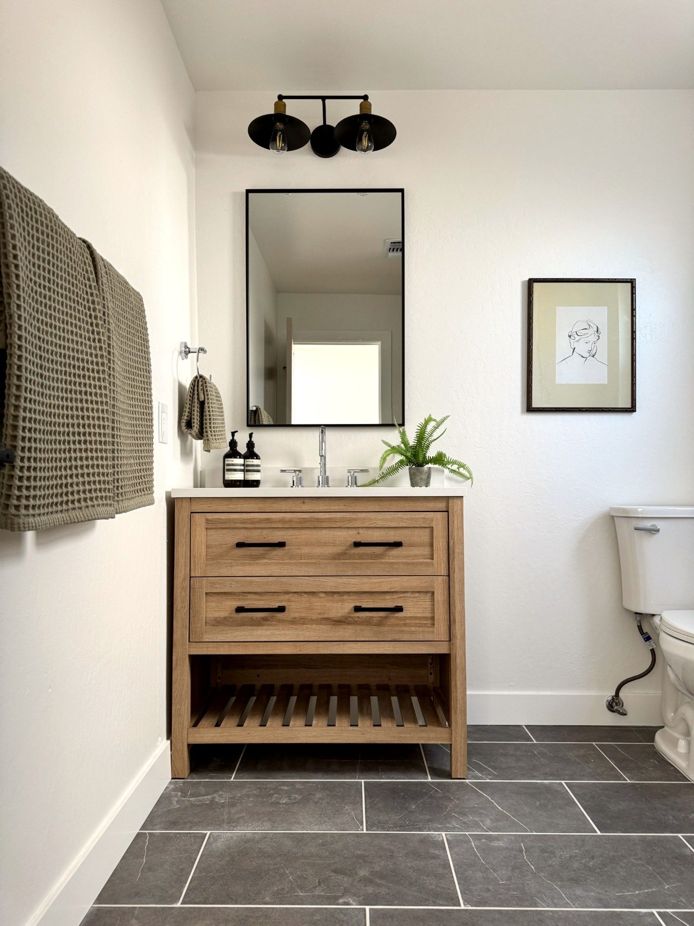 Completed Martinez bathroom with a wood vanity, dark floor tile, and walk-in shower