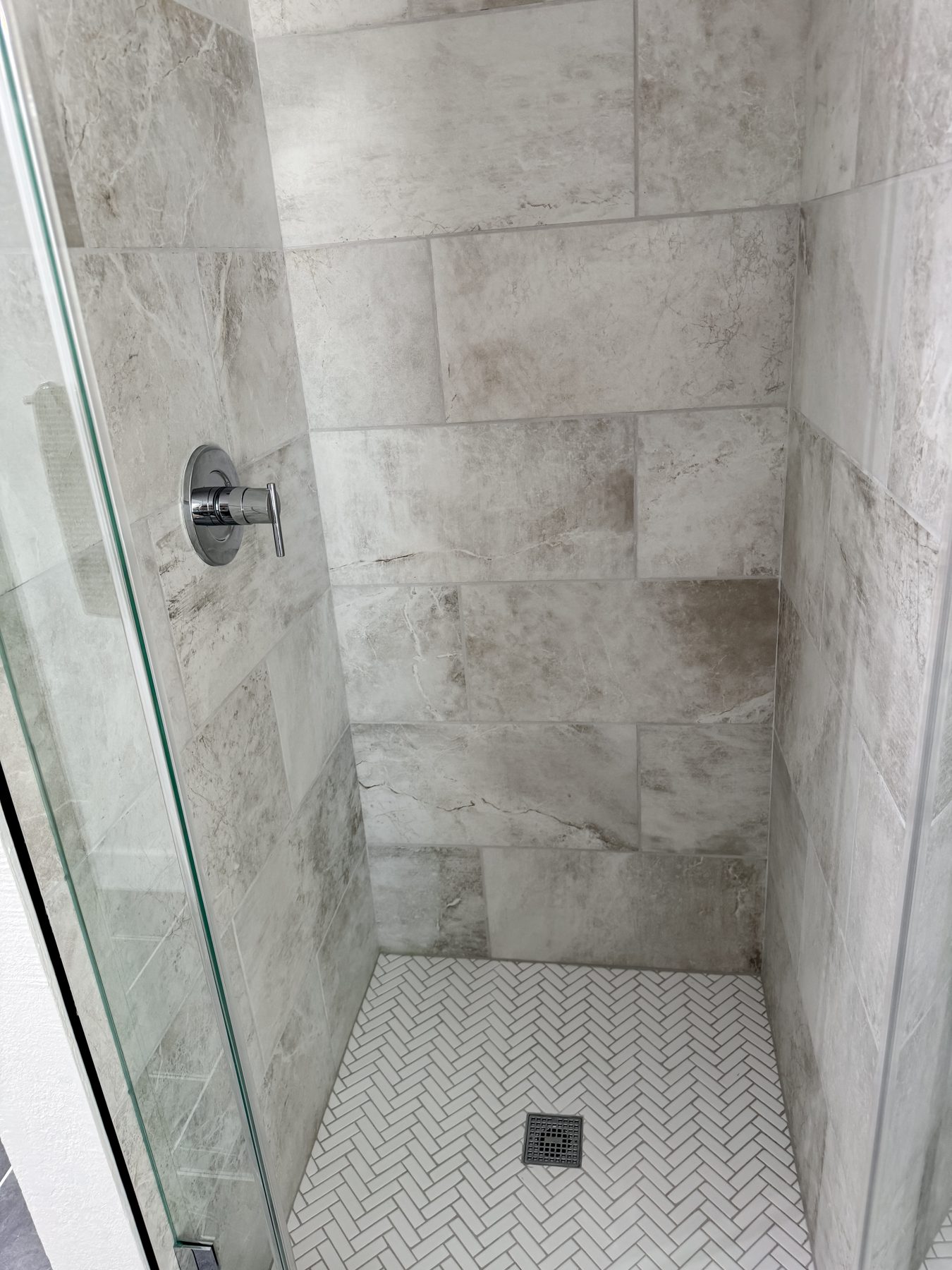 Large format tile and mosaic floor in a completed walk-in shower